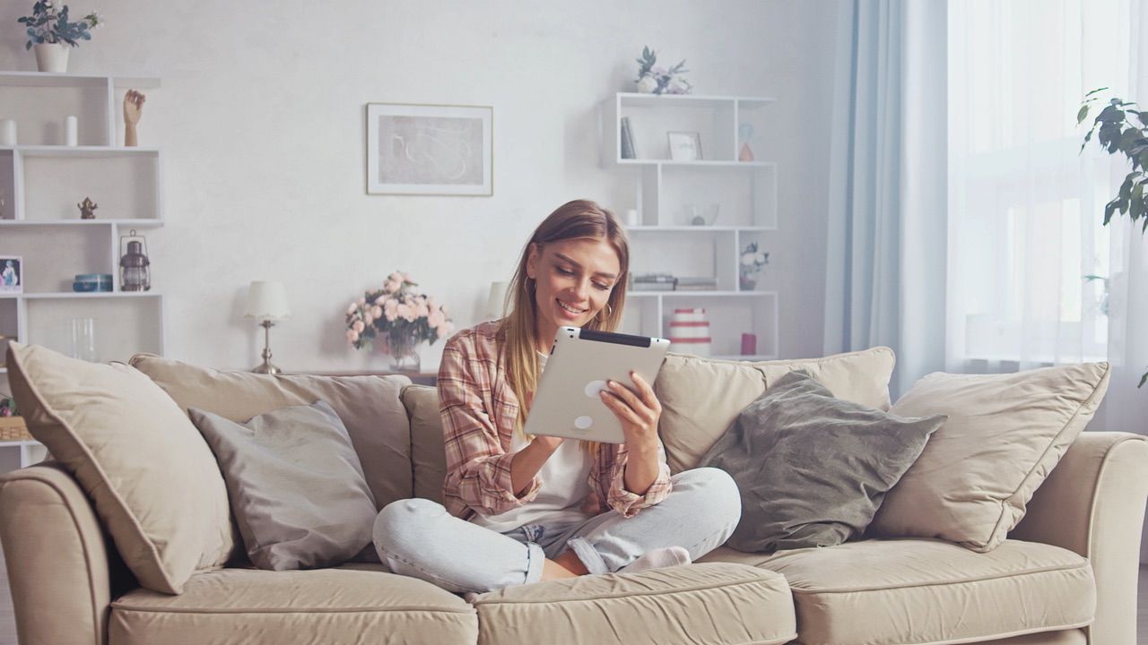Kvinna sitter i soffan på hennes surfplatta